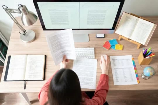 Traductora profesional realizando una comprobación de contenido utilizando su PC y notas en un escritorio